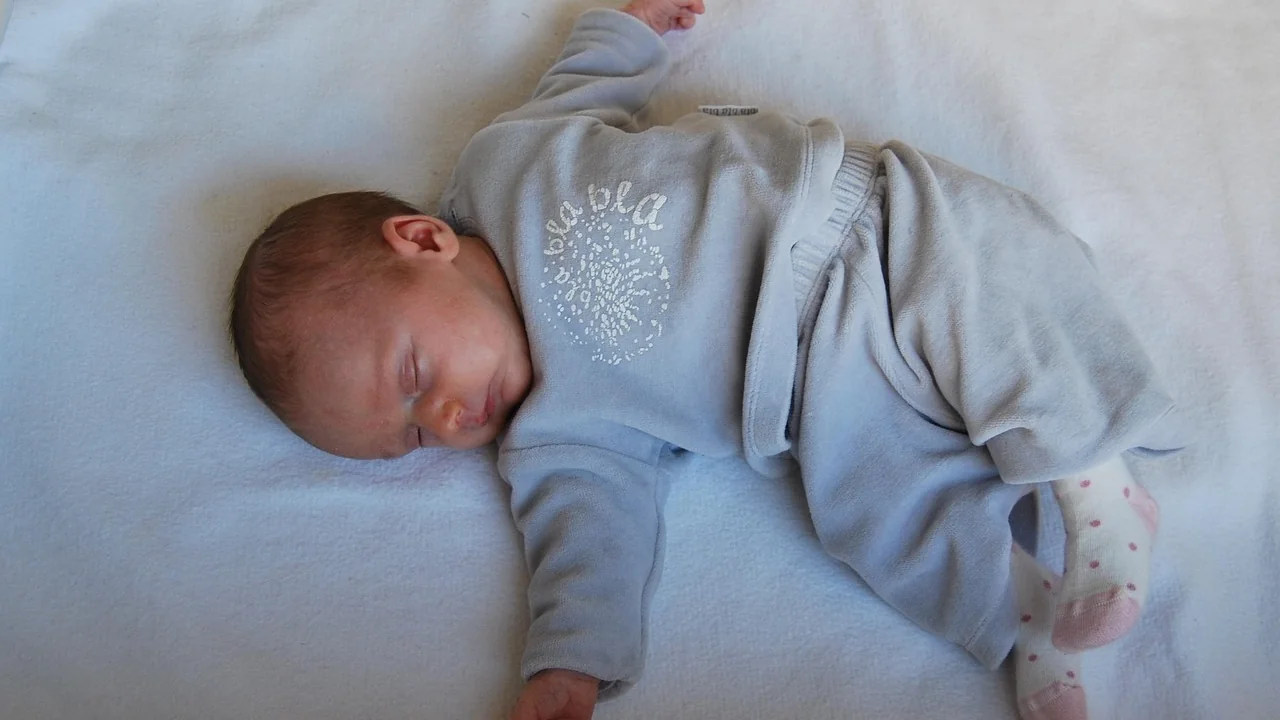Un bébé endormi sur le dos en pyjama, sur un matelas plat, sans rien autour de lui